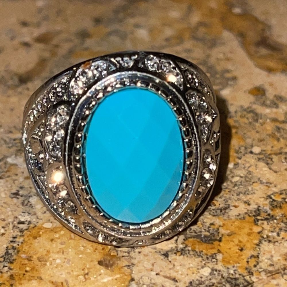 Costume jewelry silver tone ring with turquoise color acrylic center stone.